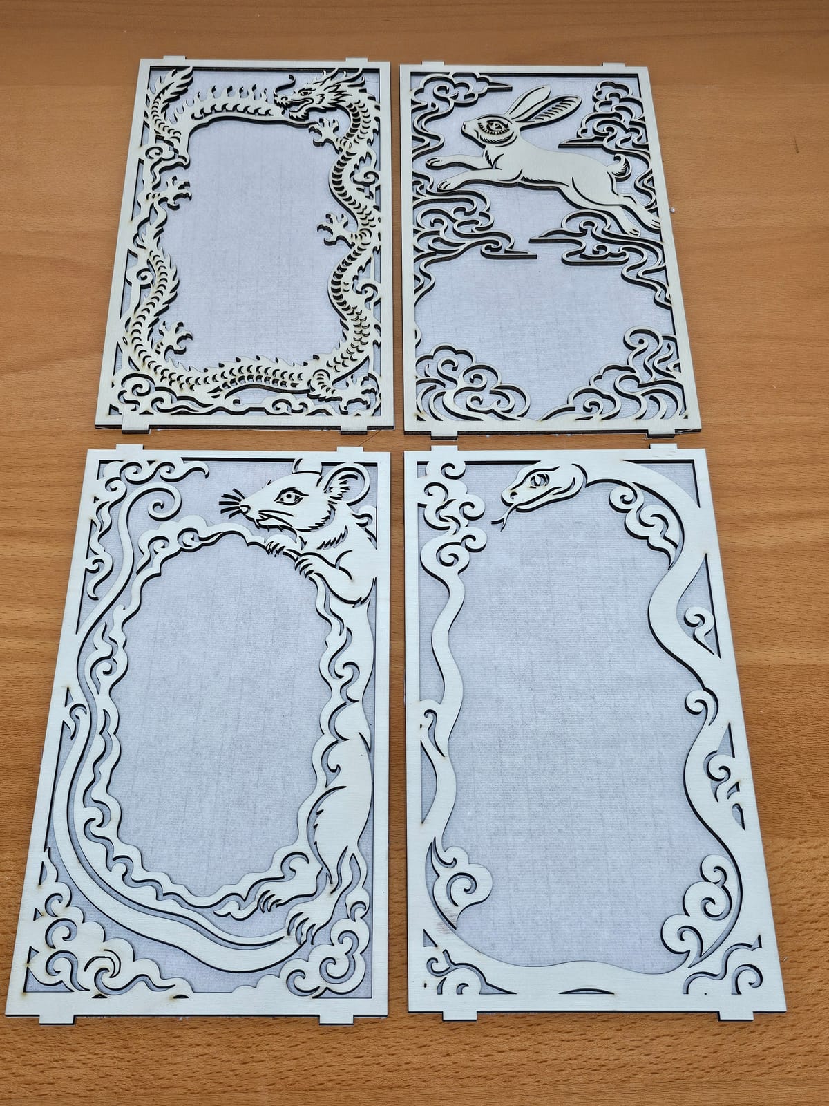 Four laser-cut panels, dragon, rabbit, rat and snake, backed with rice paper