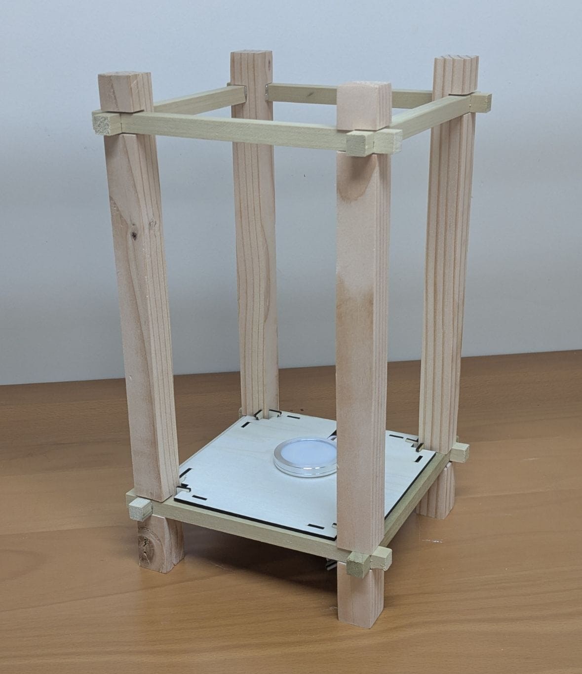 The bare wooden frame: four posts joined by notched rails, with the lamp on the base plate
